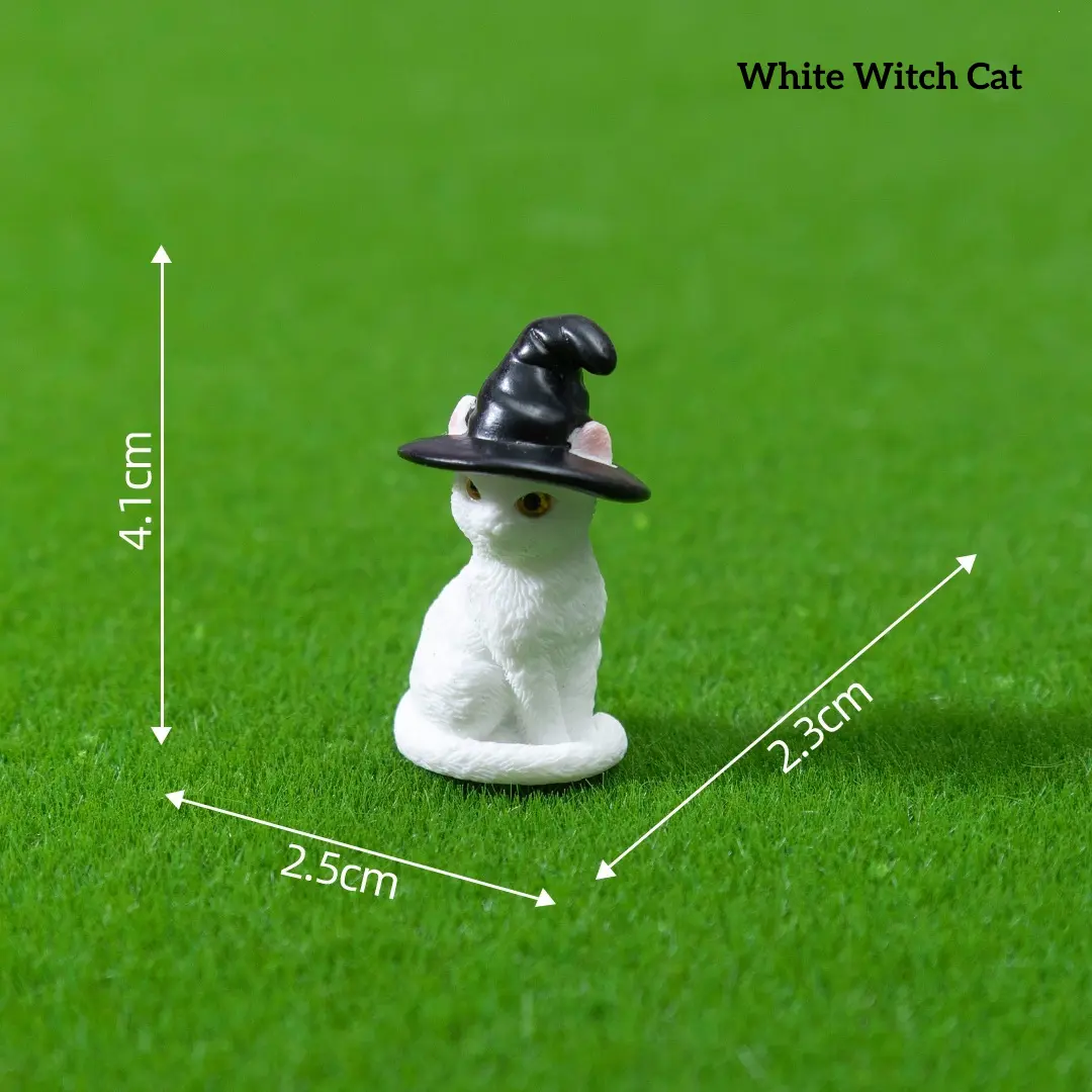 White cat wearing black witch hat fantasy miniature accessories on green grass