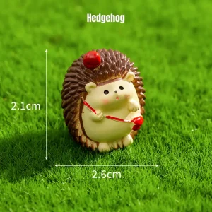 Cute hedgehog miniature animal figurines holding red apple on green grass