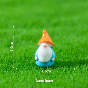 Tiny gnome miniature fairy characters with orange pointed hat on green artificial grass